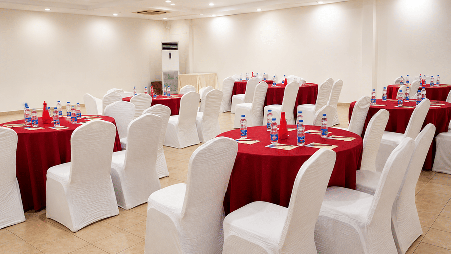 Pre Function Area arranged with round tables in red linens and white chairs at Chariot Beach Resort, suited for elegant gatherings.