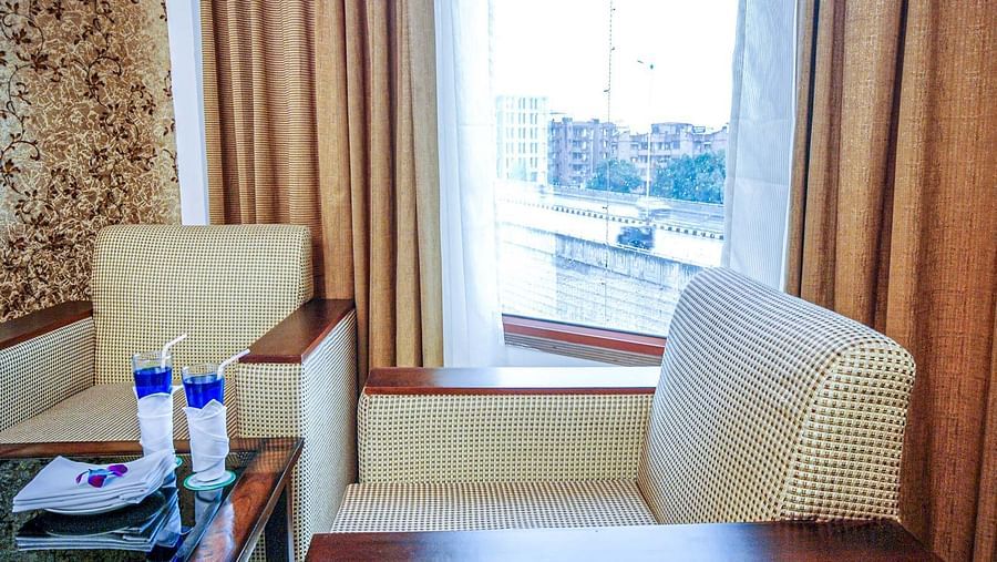 Two sofa chairs and a coffee table in a room with a glass window Sun Park Hotel & Banquet, Chandigarh - Zirakpur