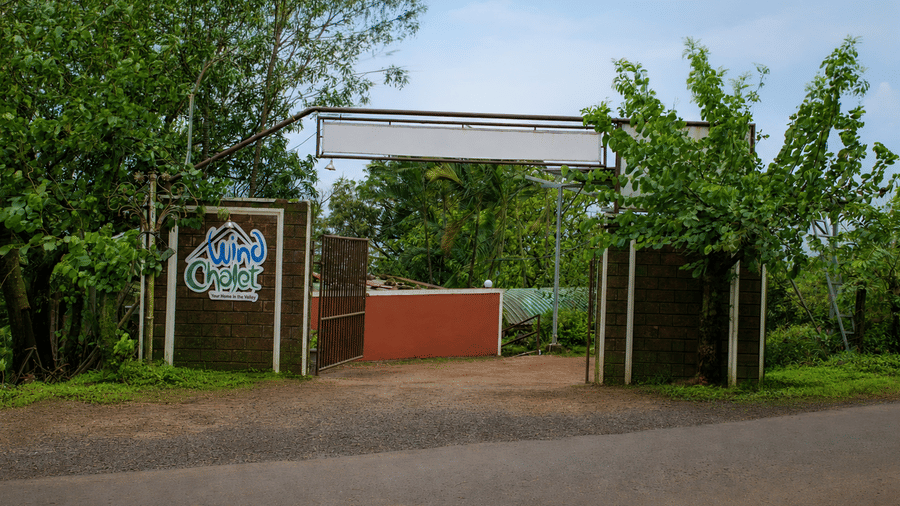 Main entrance to Wind Chalet, featuring a covered entry structure, property signage, a paved driveway, and surrounding trees.