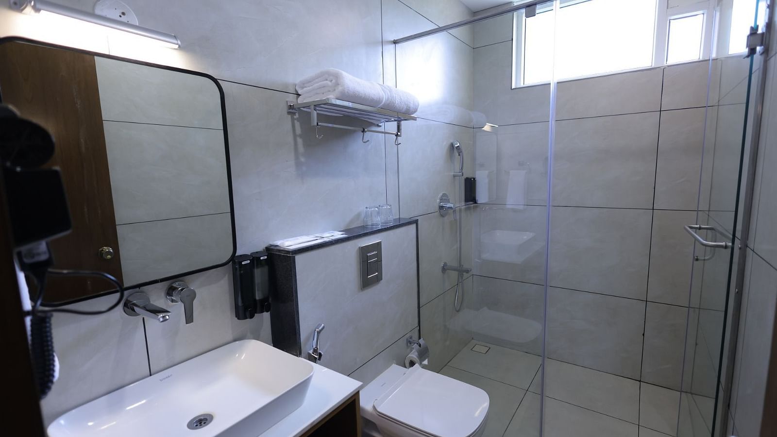 A Restroom with shower area, mirror and towels at Trishvam Symphony, Krishnagiri.