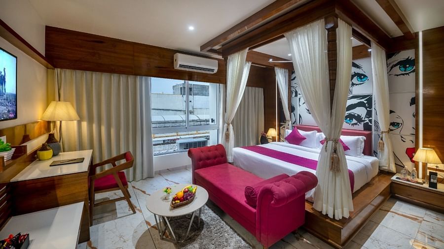 A room with a spacious bed, a small table with chairs, and a window with curtains at Angel Lords Eco Inn Amreli.