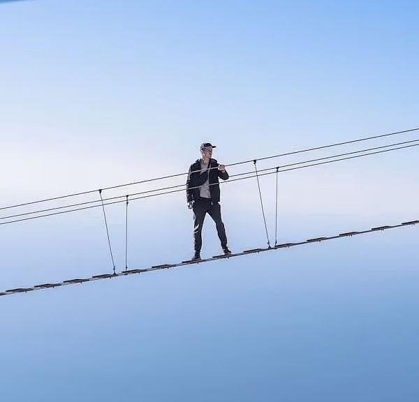 A person walking on a bridge with a clear sky in the background.