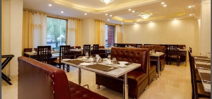 A dining area in La Serene Valley Resort in Manali. The dining room is well-lit and dining tables. | DLS La Serene Manali