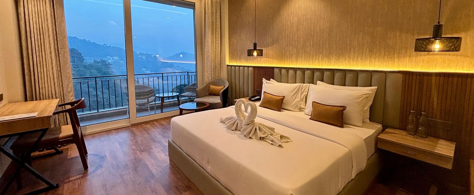 Elegant bedroom with large windows, wooden accents, and a scenic balcony view – ARNISA Boutique Hotel