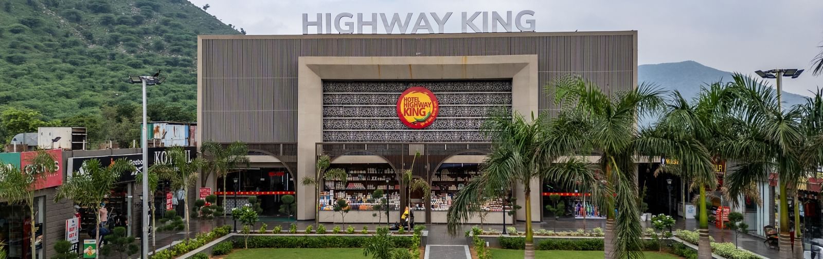 Grand exterior facade and manicured lawn leading up to the hotel entrance at Hotel Highway King, Neelka.