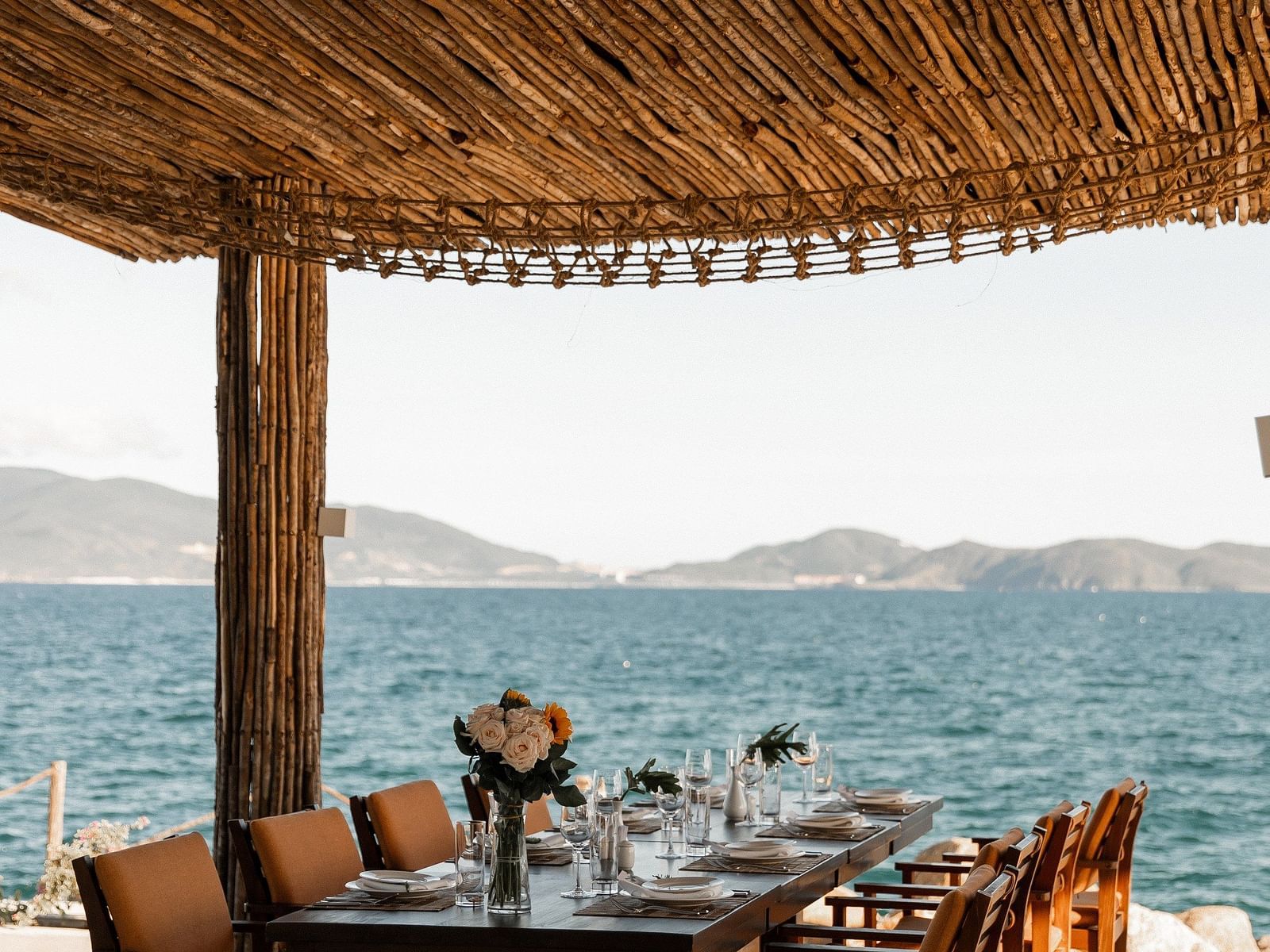 A seating arrangement under a wooden shack by the bay of Nha Trang - Alibu Resort Nha Trang