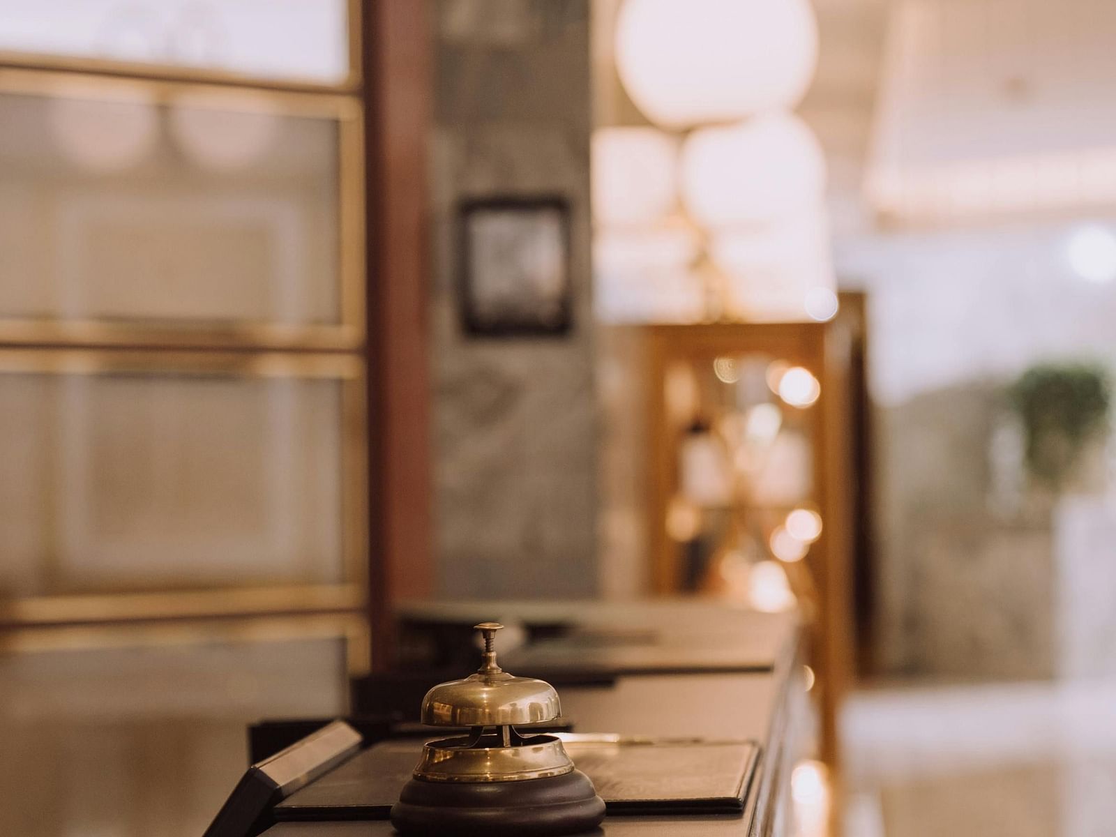 Bell kept on a hotel reception desk with warm lighting.