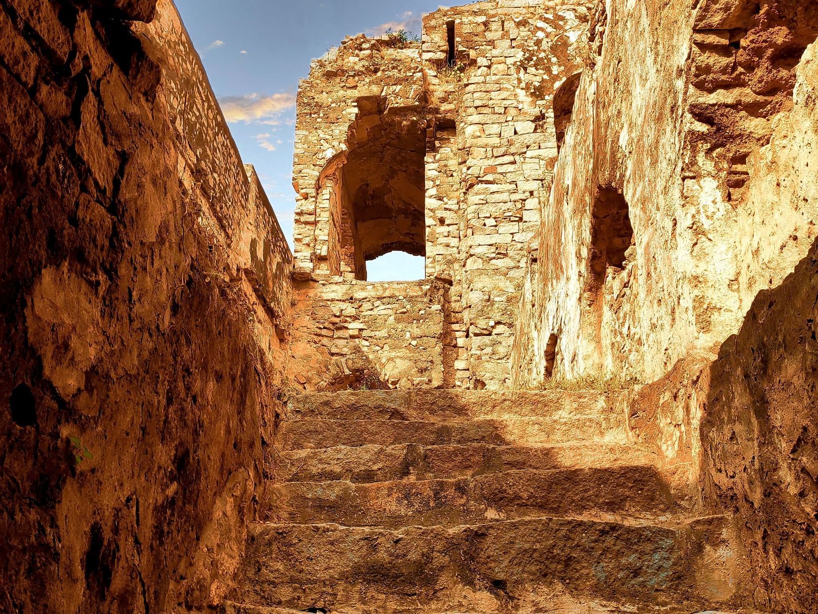 Steps inside a cave leading to the chandragiri fort with dark skies in the background