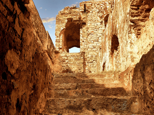 Steps inside a cave leading to the chandragiri fort with dark skies in the background