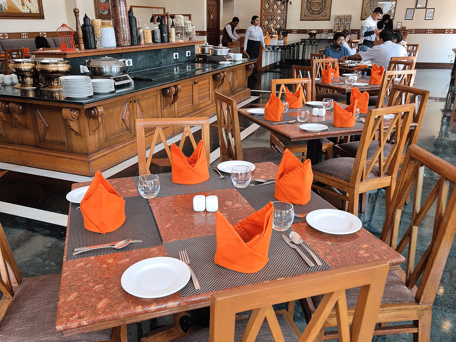 Jacaranda seating area featuring tables and chairs, illuminated by bright natural light at The Ummed Ahmedabad.