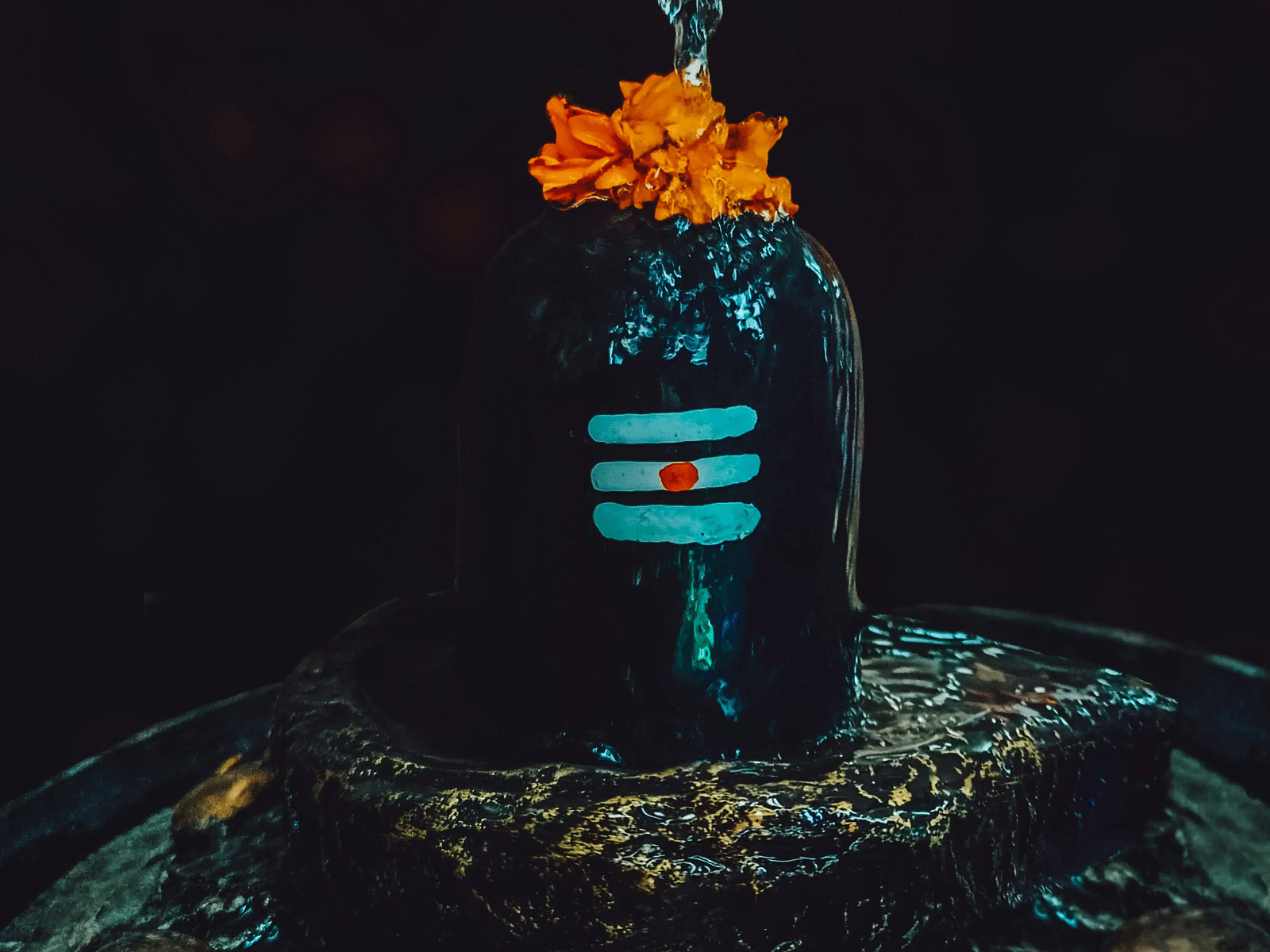 Shiva Lingam adorned with flowers and snake sculpture.