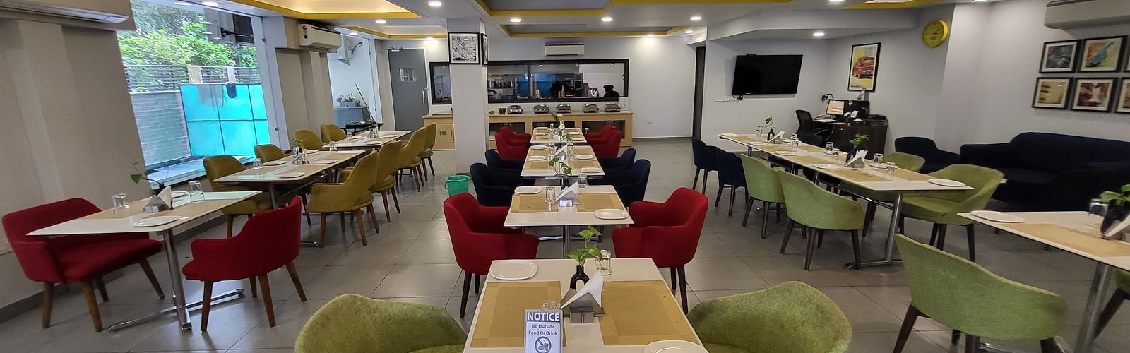 An image of a restaurant at Inde Hotel Golf Course Extension featuring several sets of chairs and tables where plates and table mats are placed