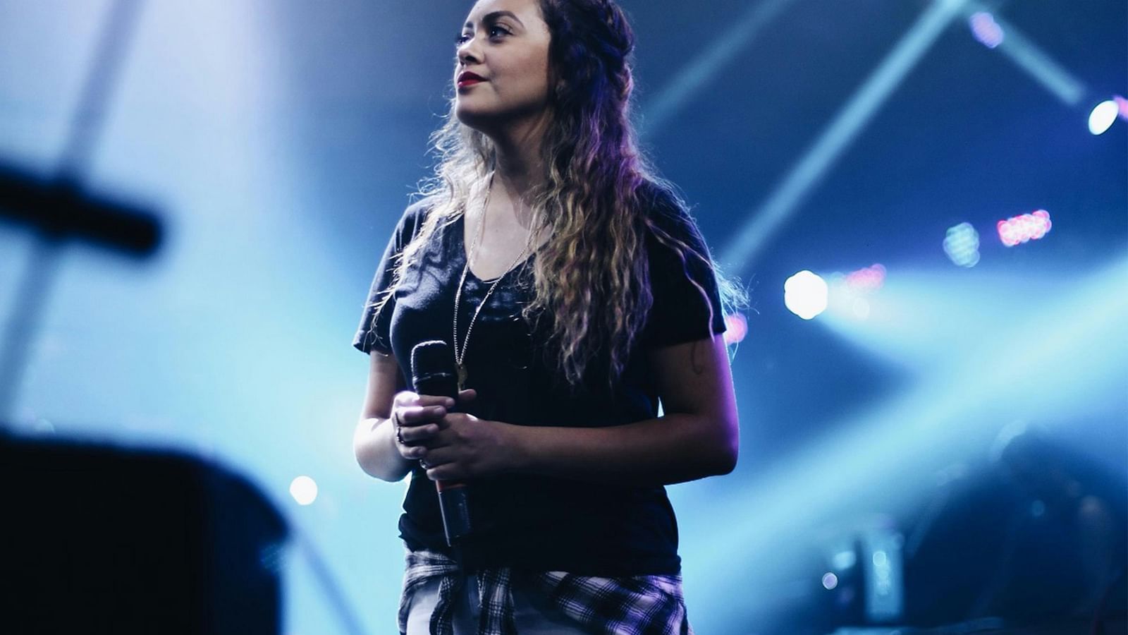 a performer holding the microphone on stage with lights in the background