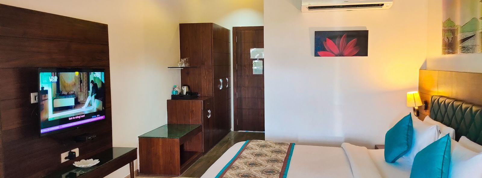 A bright, modern hotel room with a TV, bed with pillows, and a patterned runner. - Bamboo Saa Resort & Spa, Udaipur