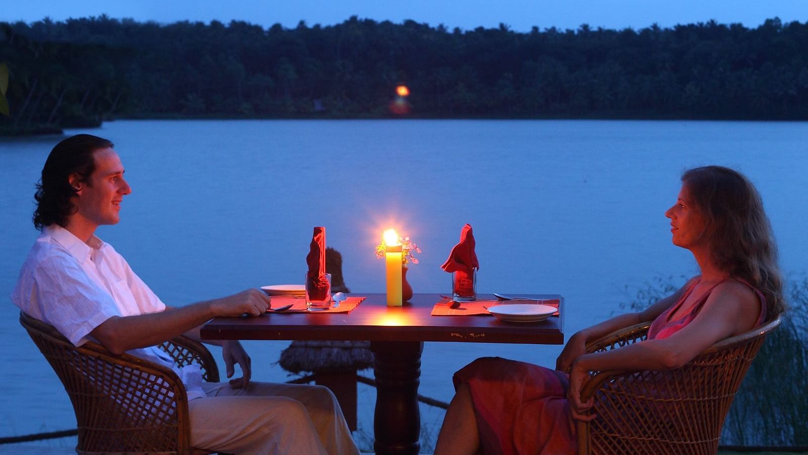 A couple enjoying a candlelit lakeside dining setup with a breathtaking view