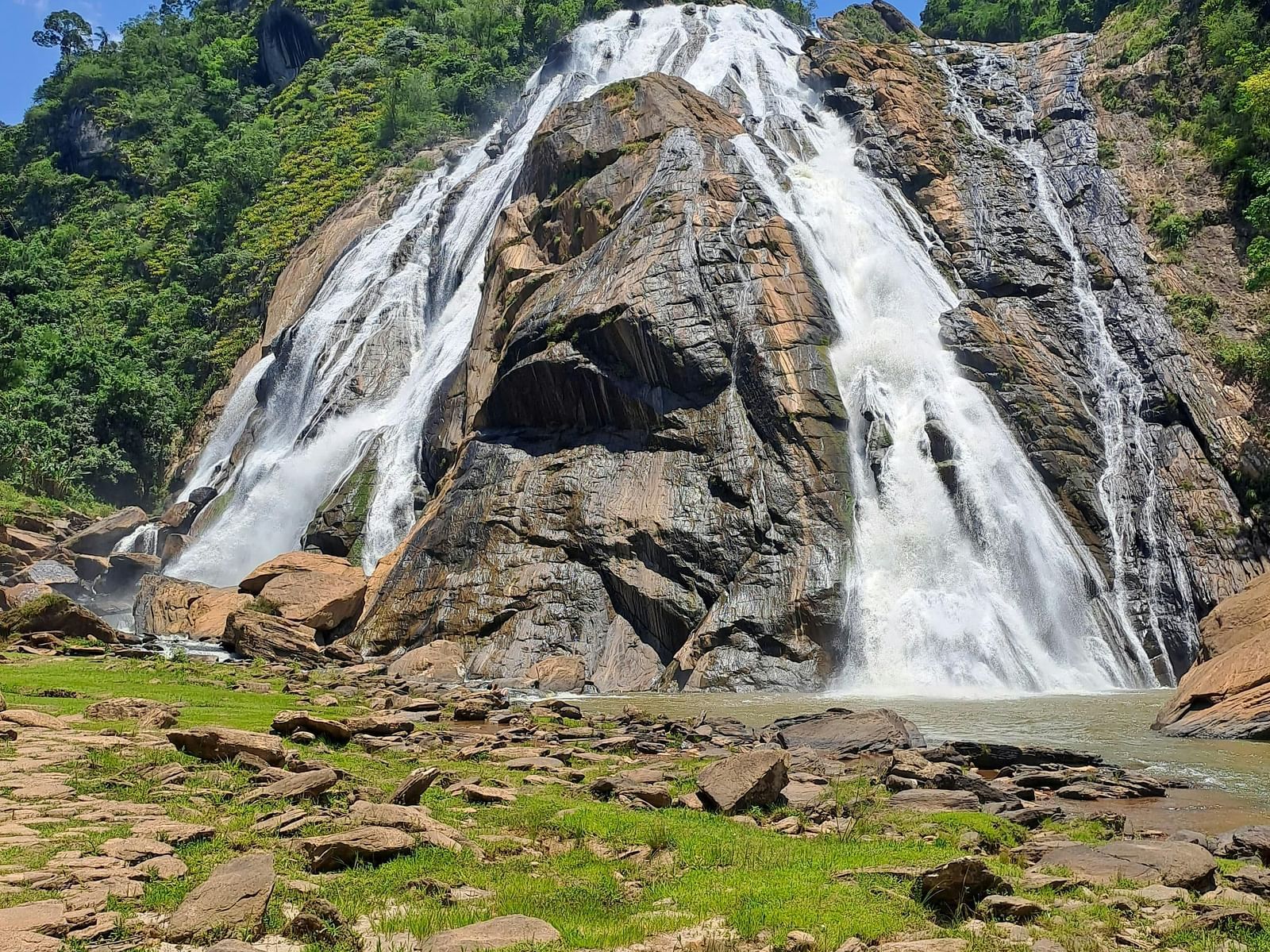 A view of the Dudhsagar Waterfall in Goa cascading through rocks on a sunny day.