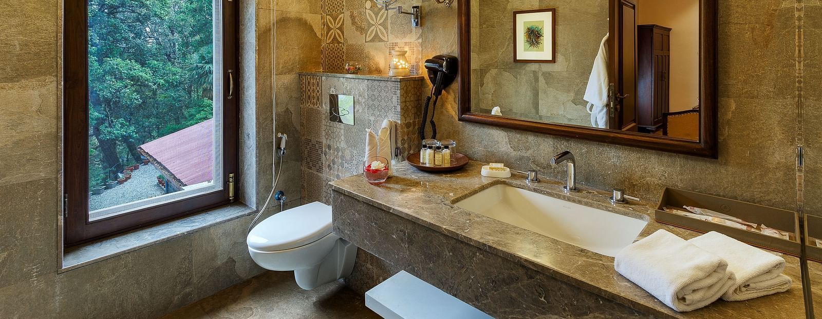 An image showing a washroom with a wooden mirror, a large window, marble floor decorated with an indoor painting - The Naini Retreat, Nainital