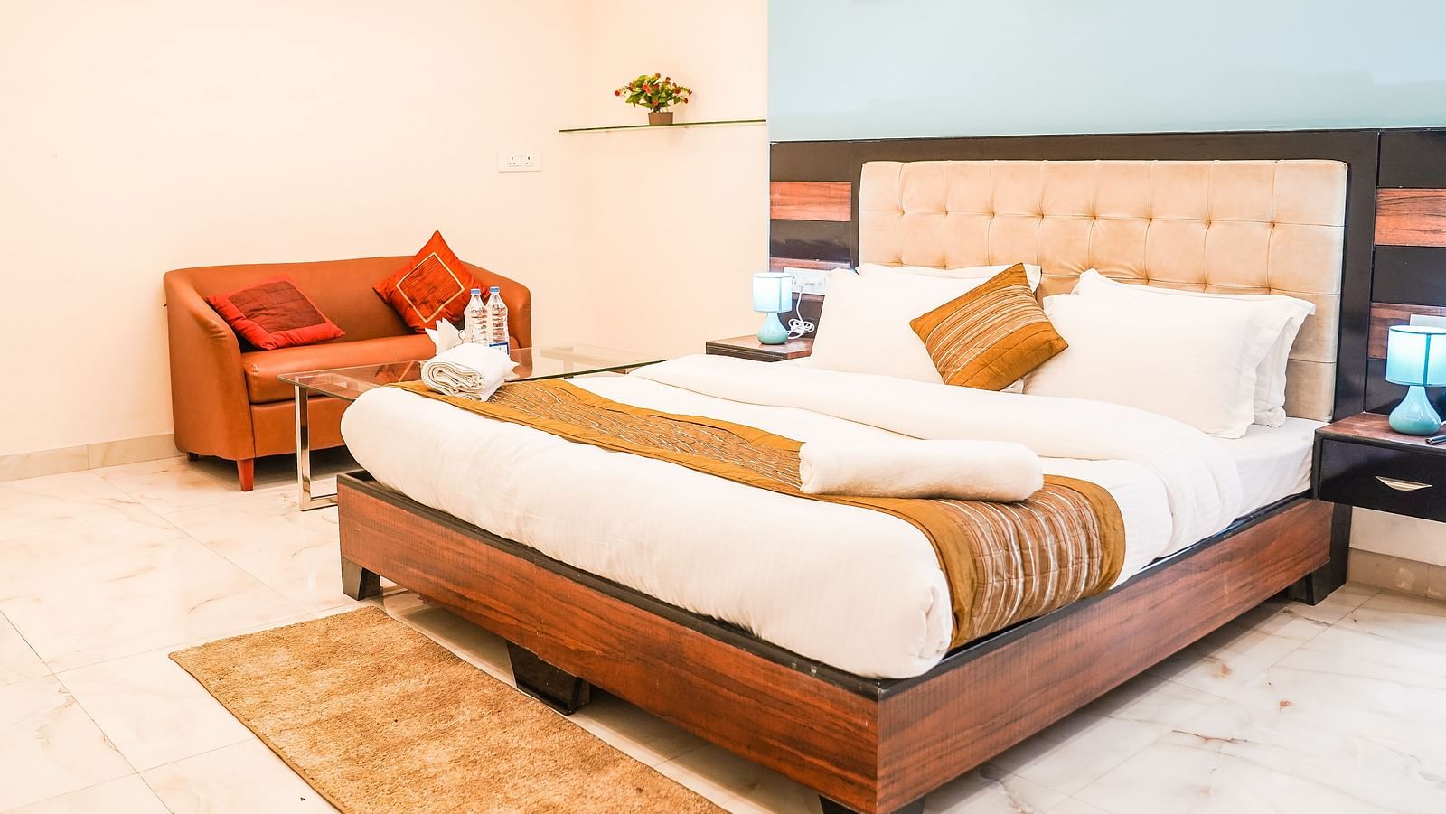 A neatly arranged room features a double bed with patterned bedding, a chair, and framed pictures on the wall - Asian Suites Cyber Park, Gurgaon