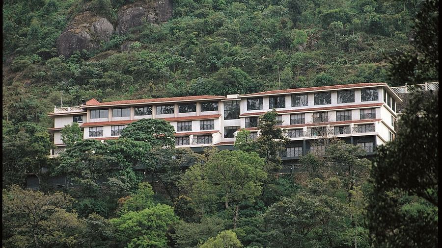 Abad Copper Castle building on a steep, green hillside, surrounded by dense foliage.