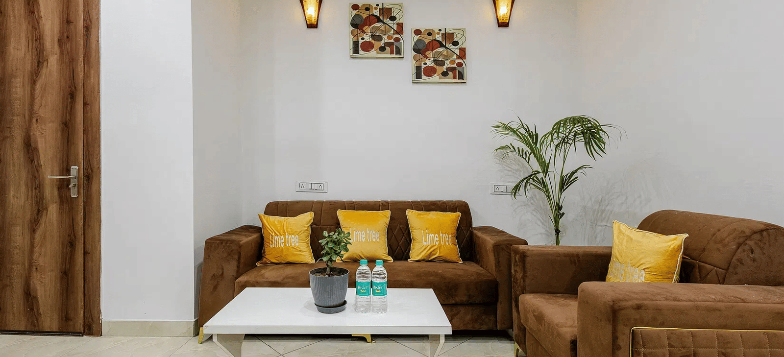 A lounge space with brown furniture, wall-mounted lights, and indoor plants - Lime Tree Hotels & Banquet, Vrindavan