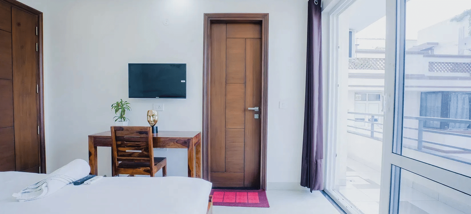 Lime Tree Hotel Golf Course Extension Road Gurgaon - A tidy bedroom with a double bed, TV, and access to a bright balcony area.
