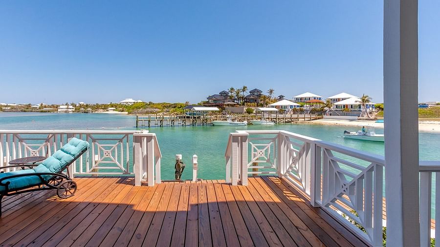 Wooden deck with blue sun loungers overlooking the water and nearby houses | Abaco Inn