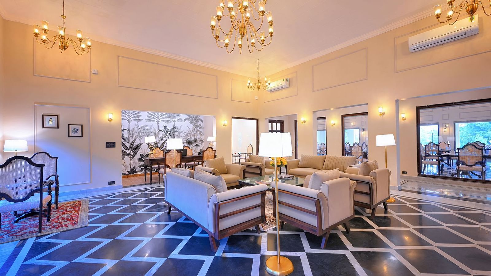 Elegant hotel lounge with beige coloured sofas, patterned flooring, chandeliers, and warm ambient lighting - Singhvilas, Ranthambore