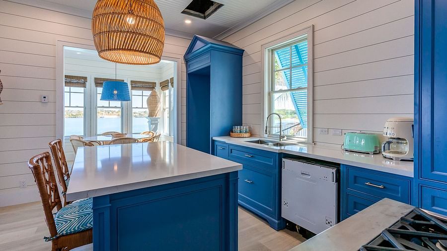 Kitchen with a navy blue island, barstools, pendant lighting, and white shiplap walls | Abaco Inn