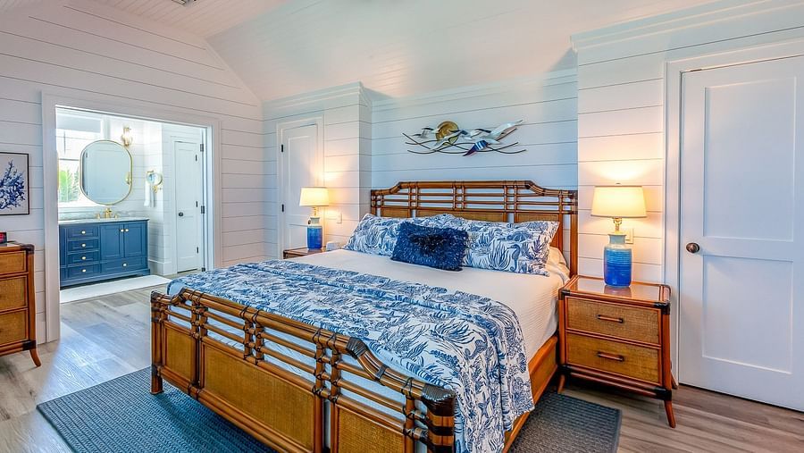 Bedroom with a wooden bed frame, blue bedding, and white coastal decor | Abaco Inn