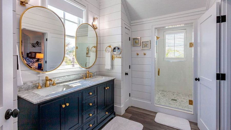 Bathroom with dual sinks, gold-framed mirrors, and a glass door | Abaco Inn