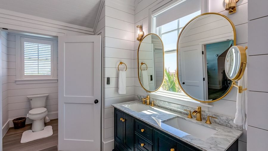 Bathroom with dual sinks, gold-framed mirrors, and a glass shower door | Abaco Inn