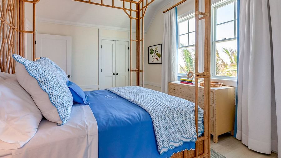 Bedroom with a bamboo four-poster bed, white and blue bedding, and soft natural lighting | Abaco Inn