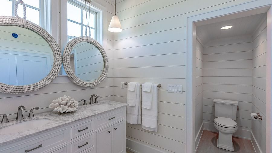 Bathroom with a white double vanity, two round mirrors, and a separate toilet area | Abaco Inn