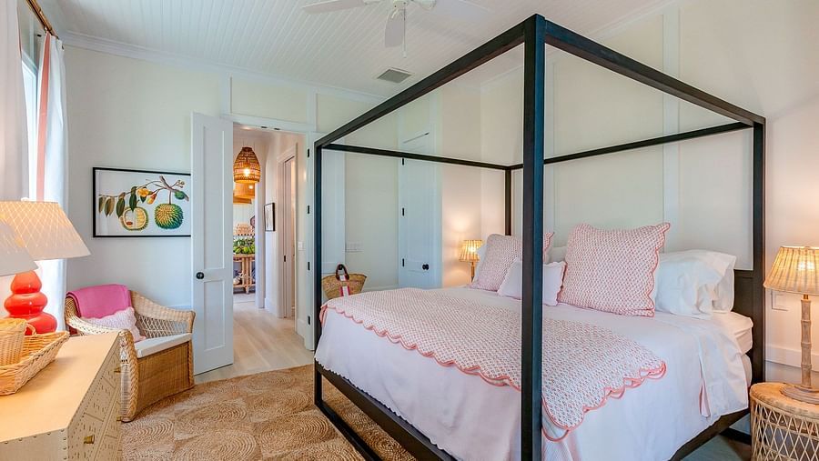 Bedroom with a black four-poster bed, white bedding with pink trim, and warm lighting from bedside lamps | Abaco Inn