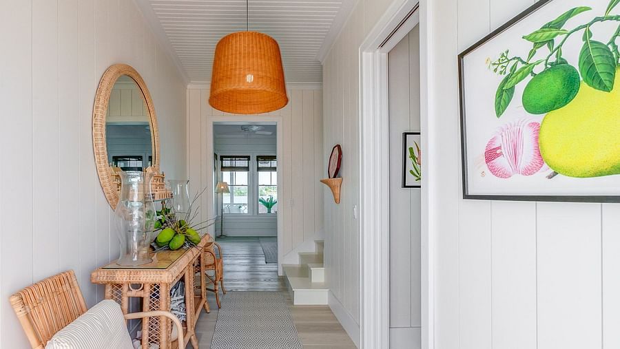 Hallway with wicker furniture, a round mirror, and an orange pendant light | Abaco Inn