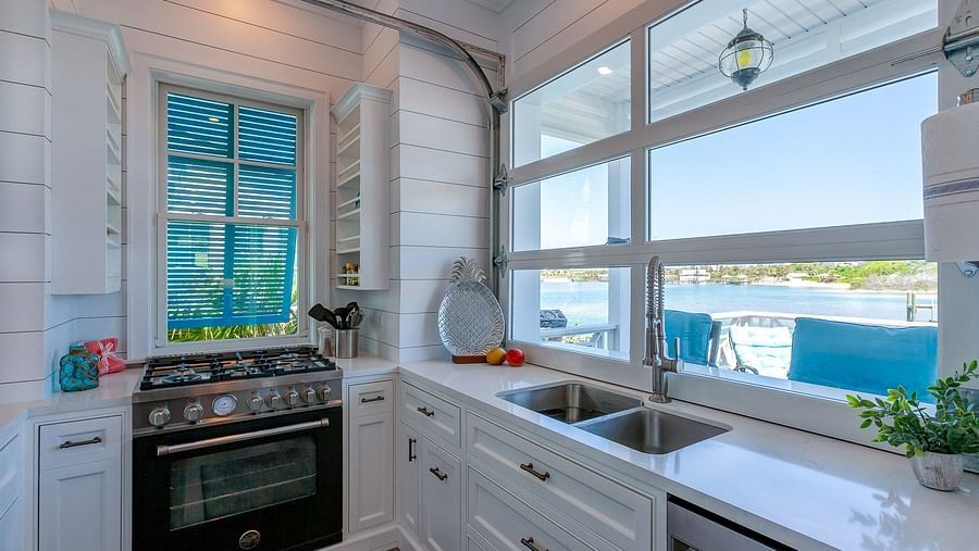 Modern kitchen with white cabinets, stainless steel oven, and large windows | Abaco Inn