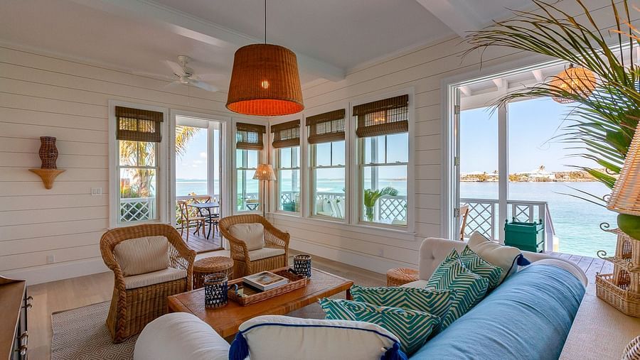 Living room with sofas, wicker chairs, and a view of the ocean through large windows | Abaco Inn