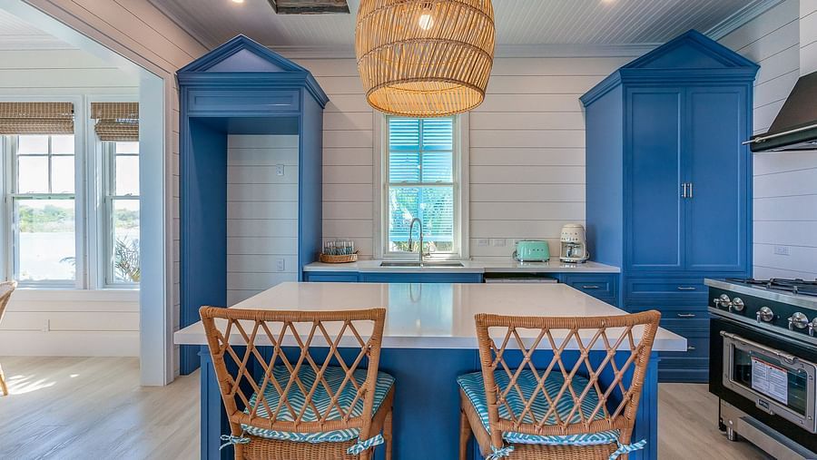 Kitchen with blue cabinets, rattan pendant lights, and a breakfast bar with wicker stools | Abaco Inn