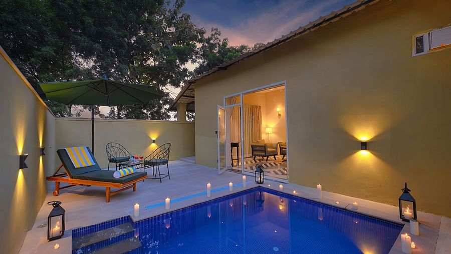 Luxury Suite Cottage with a small, illuminated private pool, lounge chairs, and an open doorway showing the interior at twilight - Singhvilas, Ranthambore
