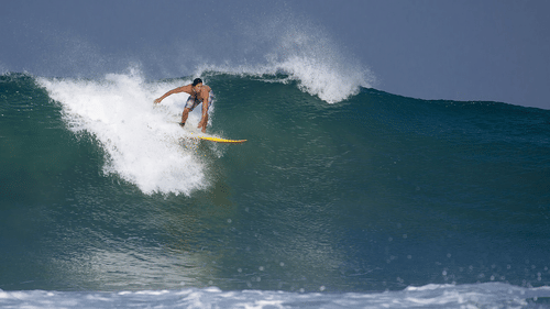A man surfing and cutting through the waves in a water body