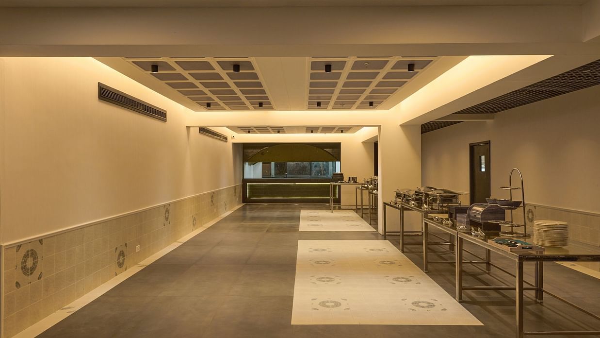 Contemporary corridor at Voyage Milestone Hotel and Banquet, leading to event spaces with seating and well-lit modern design.