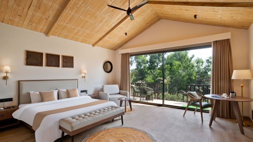 A spacious Premium Cottage room with modern decor, natural lighting, and a balcony overlooking nature.