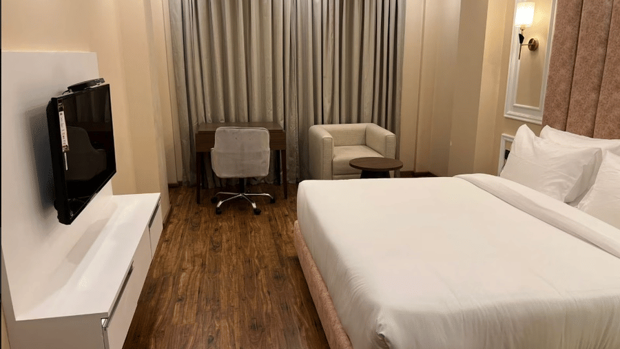 Spacious bedroom with plush bedding, seating space, and soft lighting for a comfortable stay at Claret Inn, Dalhousie.