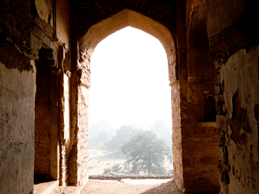 The interior of a fort with an arched opening overlooking a foggy exterior.