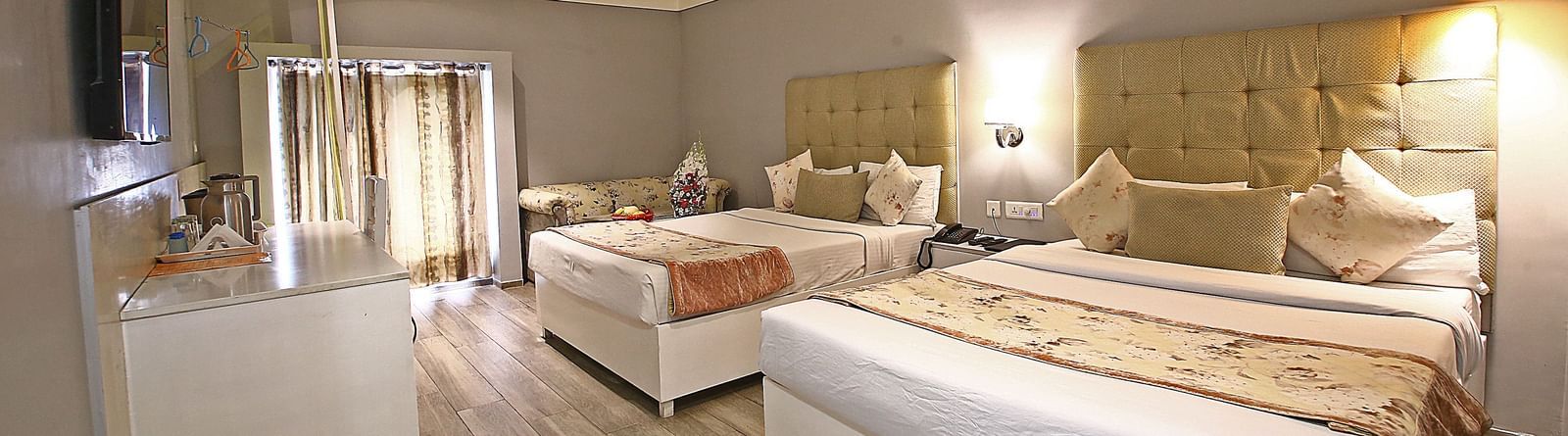 Spacious hotel room with twin beds, wardrobe, and natural light at Hotel Emerald