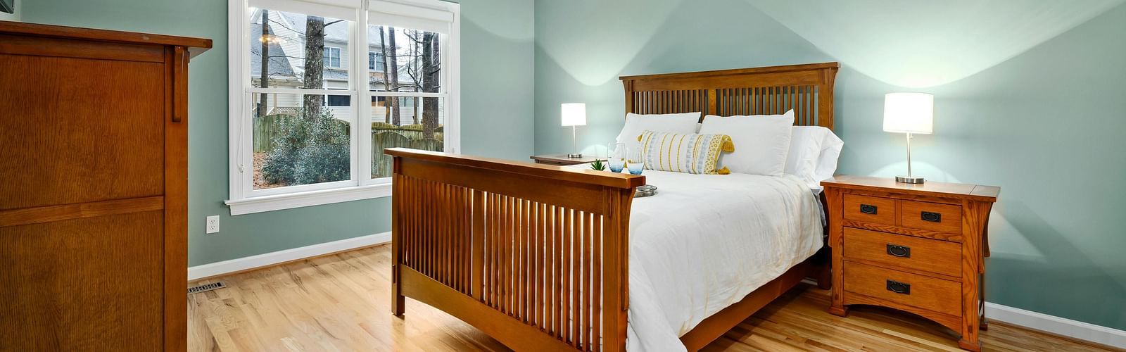 A bedroom with a double bed, a side table and a cupboard
