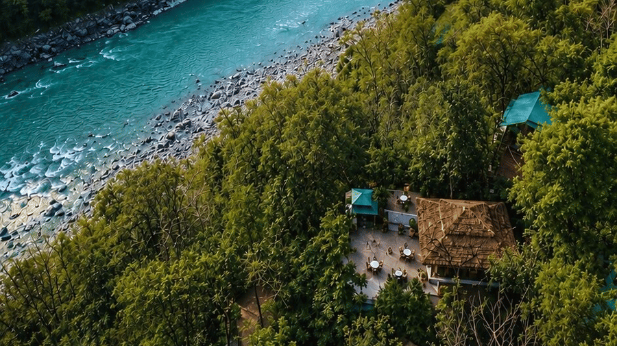 Aerial view of the turquoise Ganges flowing through forested mountains near Neemrana's Glasshouse on The Ganges - 21st Century, Rishikesh.