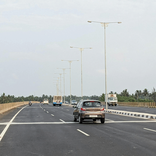 Cars driving along a wide multi-lane highway under a clear sky during a road trip between Bangalore and Tirupati.