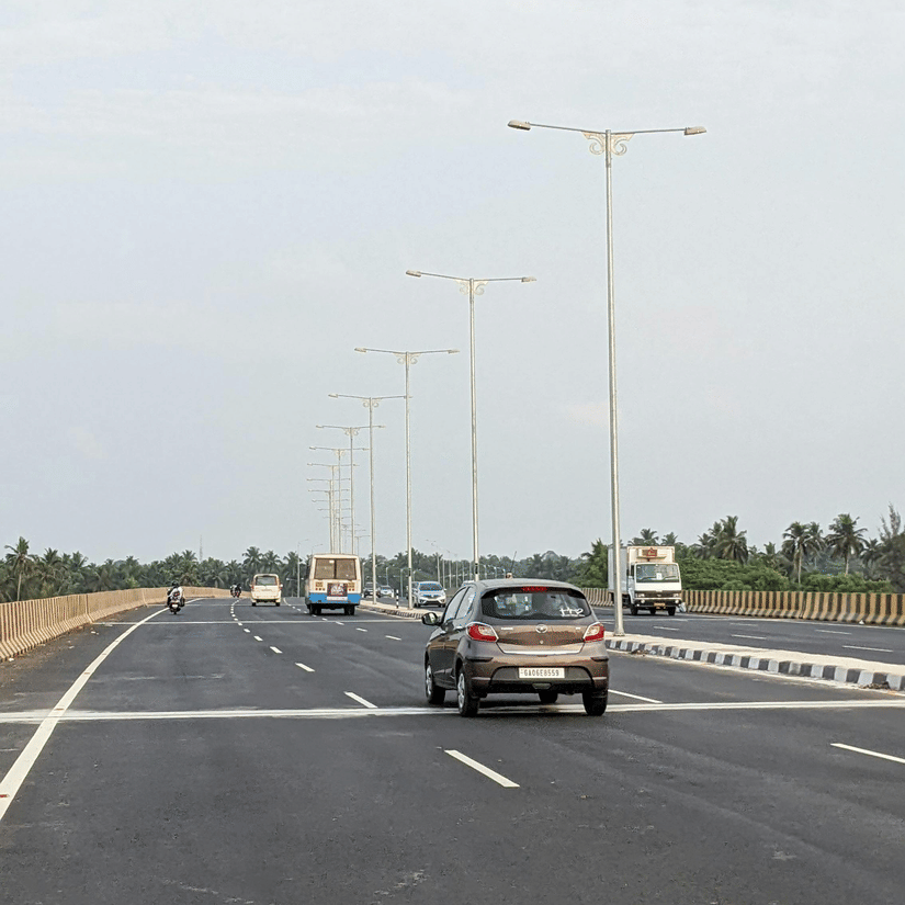 Cars driving along a wide multi-lane highway under a clear sky during a road trip between Bangalore and Tirupati.