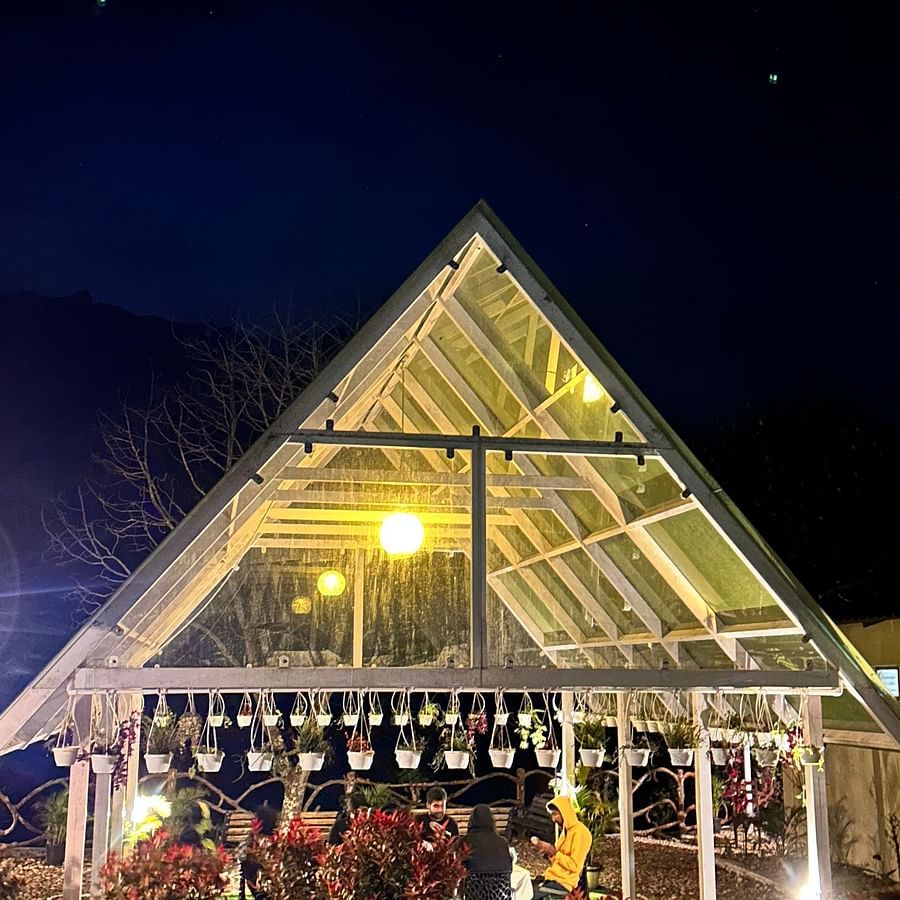an image of night view of glass roof illuminating yellow lights at Ibex Stays & Trails, Valparai (Mistly)